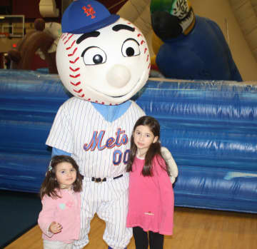 Two Lazzaro sisters, Aoife. left, and Maeve. right, of Carmel, pose with Mr. Met, who made a special appearance at the Children's Carnival for Charity at The Harvey School. 