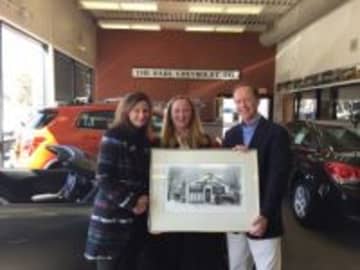 Photo Displaying a pen-and-ink drawing of the original KARL Chevrolet dealership on Railroad Avenue (now Elm St.) in New Canaan are (left to right) Arianne Kolb and Eleanor Flatow, co-directors of the Carriage Barn; Steve Karl, VP of  Karl Chevrolet.