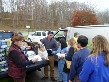 Sen. Greg Ball, center, helps distribute dry ice and water at the Lewisboro Town House on Tuesday as Town Clerk Janet Donohue, far left, looks on.