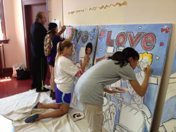Togetherhood volunteers with the Rye YMCA work with local artist Daniel DeNapoli on a triptych that will brighten the walls of the Don Bosco Community Center language and literacy center.