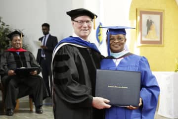 Seminary president Hugh Spurgin hands a diploma to Sister Christiana Mmadu of Nigeria during commencement exercises at the Unification Theological Seminary in Barrytown on Saturday.