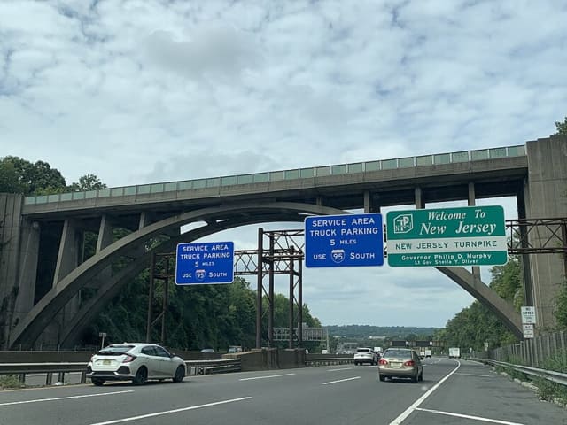 <p>The New Jersey Turnpike and I-95 southbound under the Edgewood Road Bridge in Leonia, NJ, with a sign welcoming drivers to the highway in August 2023.</p>